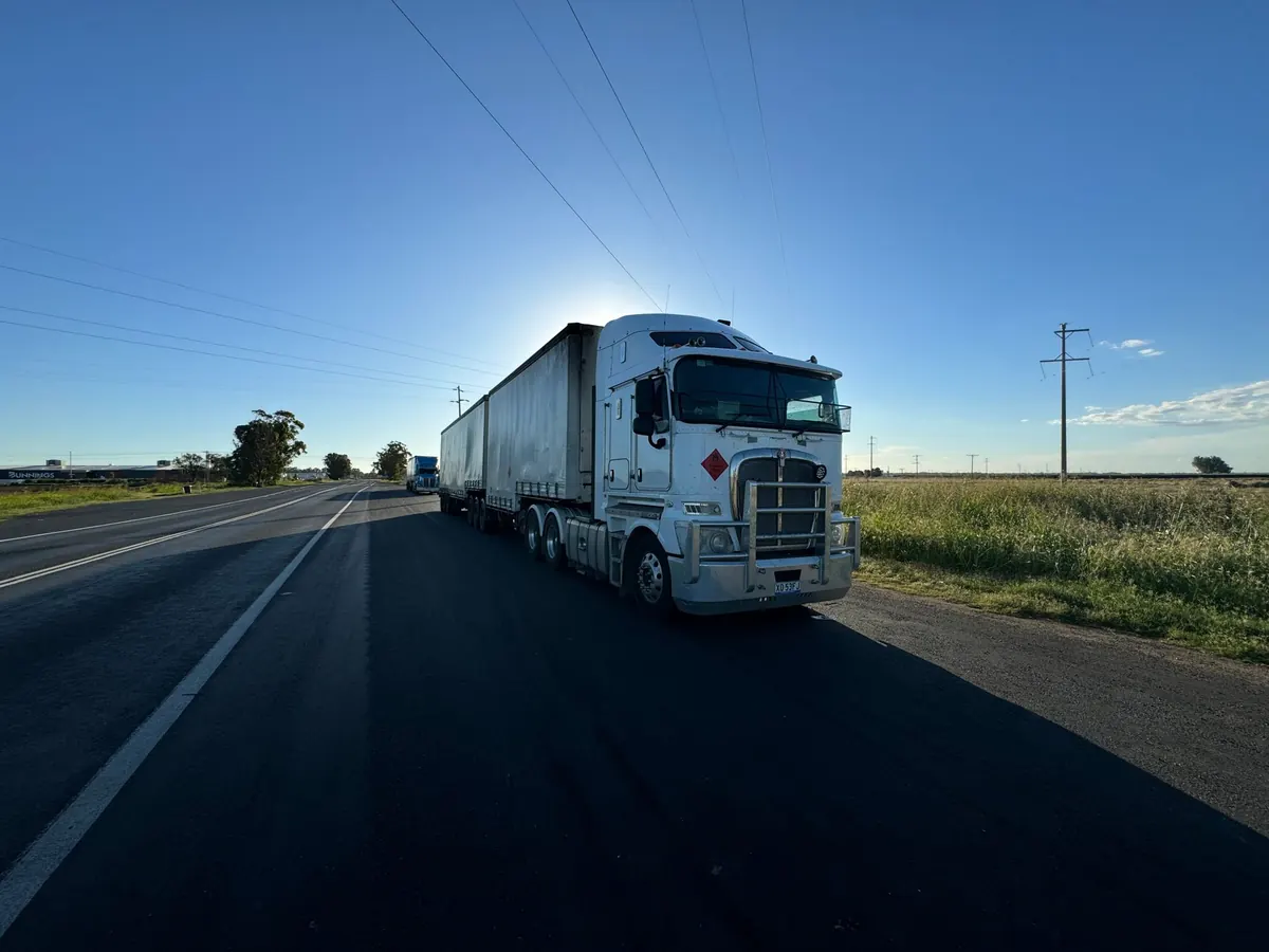 Caminhão prateado numa rodovia sob céu azul